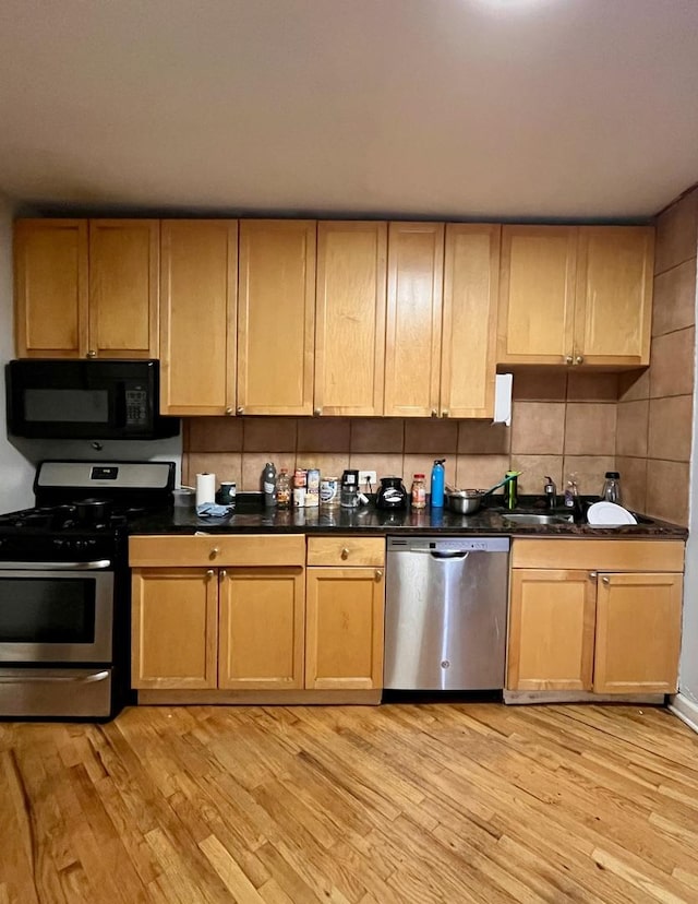 kitchen with sink, stainless steel appliances, tasteful backsplash, and light hardwood / wood-style flooring