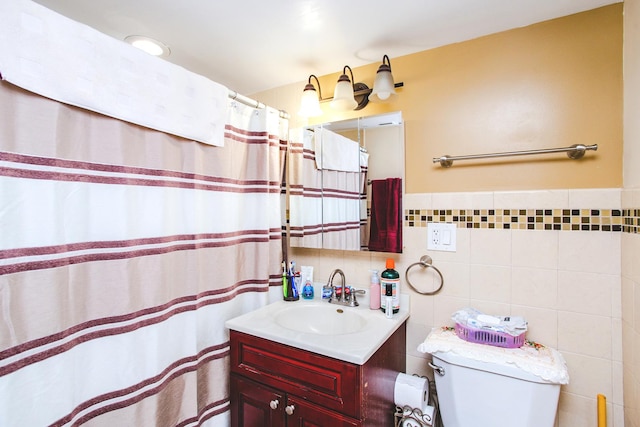 bathroom with vanity, toilet, and tile walls