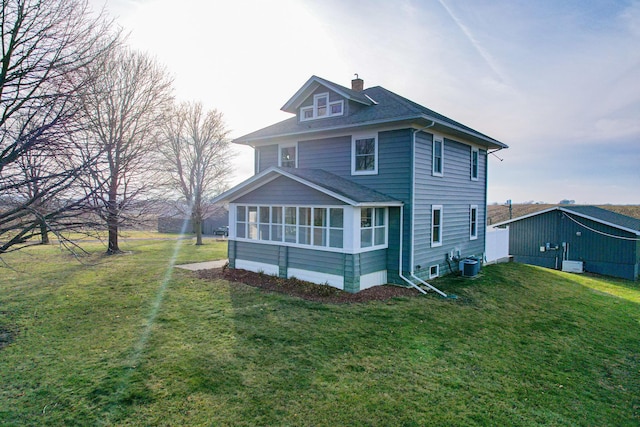 rear view of house with a sunroom, cooling unit, and a lawn