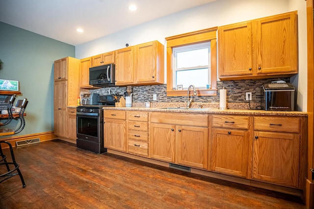 kitchen with dark wood-type flooring, sink, stainless steel stove, and tasteful backsplash