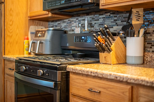 kitchen with gas stove and tasteful backsplash