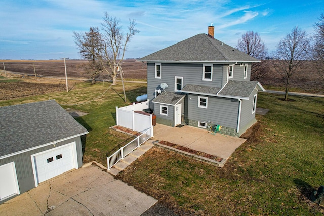 rear view of property featuring a yard, a garage, and an outdoor structure