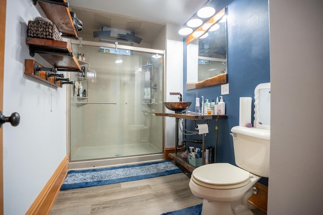 bathroom featuring hardwood / wood-style floors, toilet, a shower with shower door, and sink