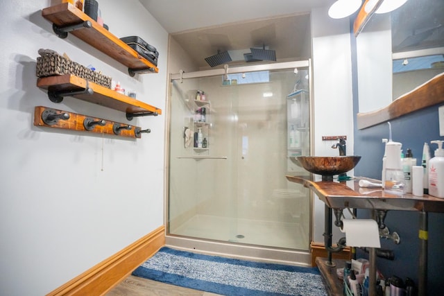 bathroom featuring a shower with shower door and sink