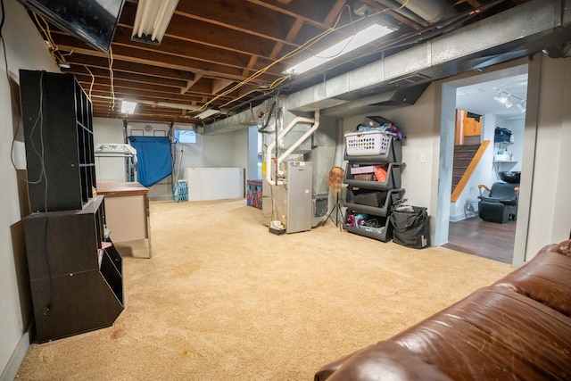 basement featuring light carpet, washer / clothes dryer, and heating unit