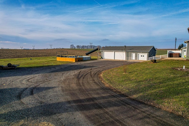 single story home featuring a garage, a rural view, and a front yard