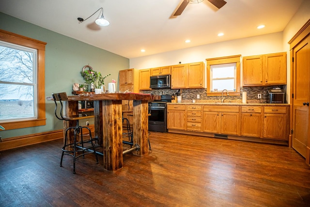 kitchen with sink, black electric range, dark hardwood / wood-style floors, backsplash, and a breakfast bar