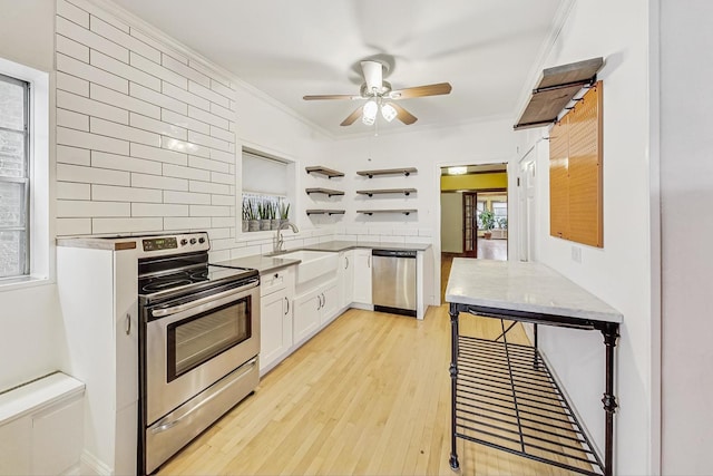 kitchen featuring white cabinetry, crown molding, light wood-type flooring, appliances with stainless steel finishes, and decorative backsplash