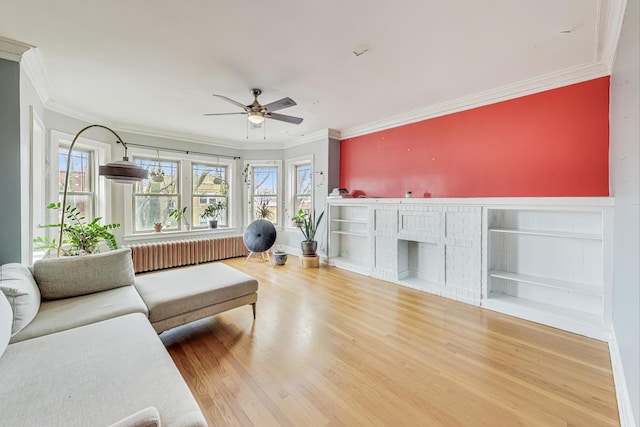 living room with radiator, a fireplace, hardwood / wood-style floors, and ornamental molding