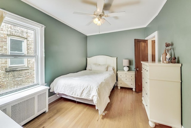 bedroom featuring ornamental molding, radiator heating unit, ceiling fan, and light hardwood / wood-style flooring