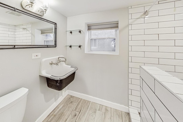 bathroom with toilet, wood-type flooring, and walk in shower