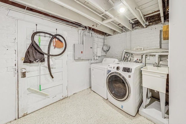 laundry area with washing machine and dryer, brick wall, and electric panel