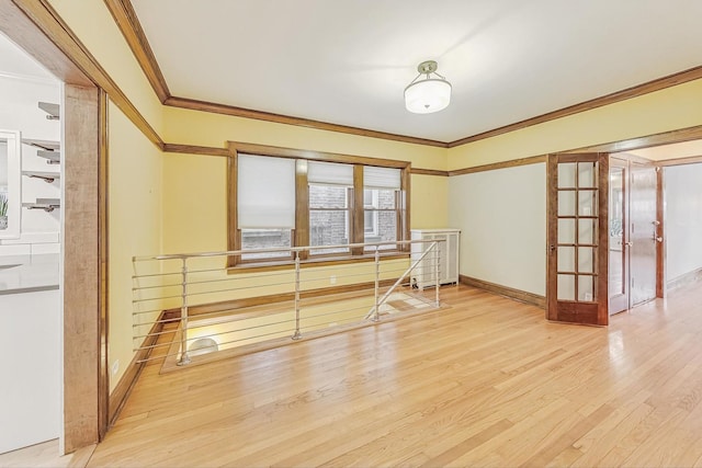 unfurnished room with ornamental molding, light wood-type flooring, and french doors