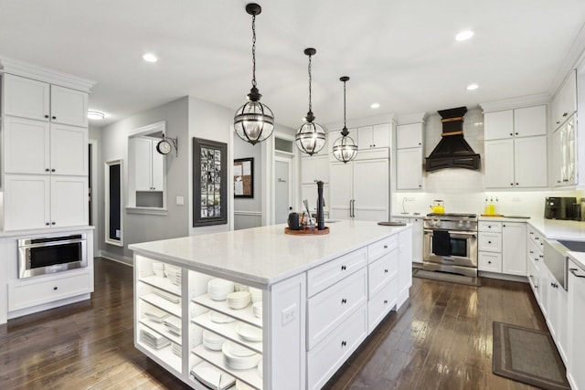 kitchen featuring a center island, stainless steel stove, premium range hood, white cabinetry, and decorative light fixtures