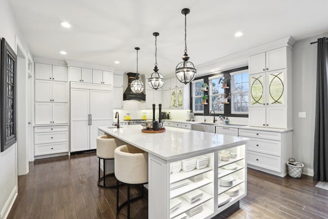 kitchen featuring decorative light fixtures, white cabinetry, an island with sink, a breakfast bar, and dark wood-type flooring