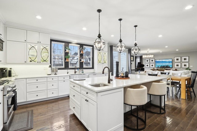 kitchen featuring an island with sink, high end range, white cabinetry, and sink