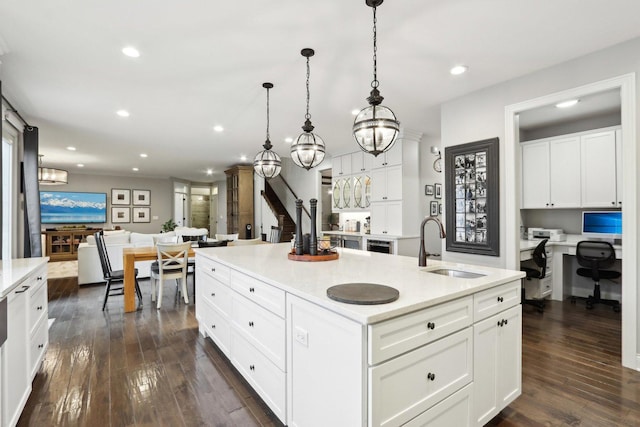 kitchen featuring sink, a center island with sink, white cabinetry, and hanging light fixtures