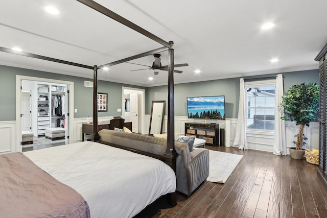 bedroom with a closet, ceiling fan, dark hardwood / wood-style flooring, ornamental molding, and a walk in closet