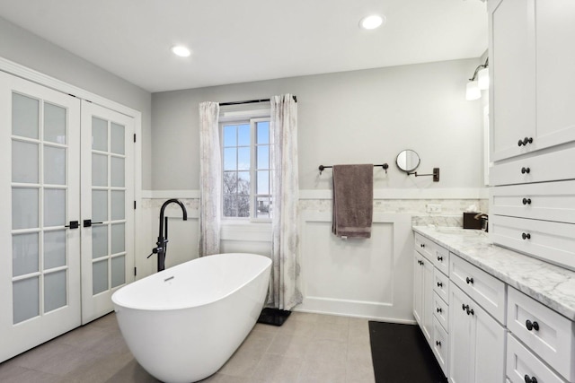 bathroom with tile walls, a washtub, tile patterned floors, and vanity