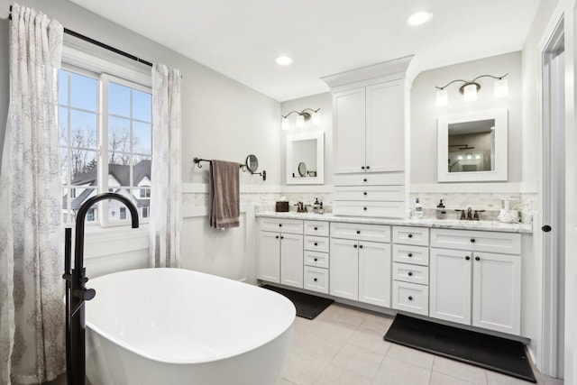 bathroom featuring tasteful backsplash, a washtub, tile patterned floors, and vanity