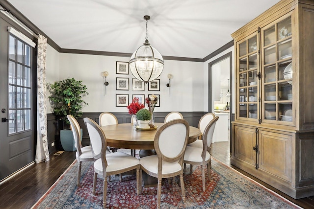 dining area featuring crown molding, a notable chandelier, and dark wood-type flooring