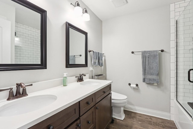 full bathroom featuring hardwood / wood-style floors, shower / bath combination with glass door, vanity, and toilet