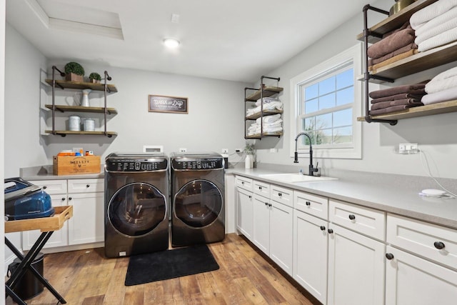 laundry area with cabinets, separate washer and dryer, light hardwood / wood-style floors, and sink