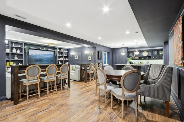 dining area with crown molding, built in features, and light hardwood / wood-style flooring