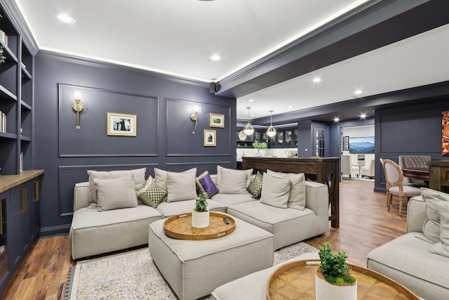 living room featuring hardwood / wood-style flooring, ornamental molding, and built in shelves