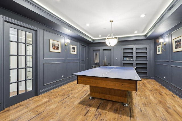 game room featuring light wood-type flooring and a tray ceiling