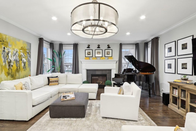 living room with an inviting chandelier, a tiled fireplace, crown molding, and hardwood / wood-style floors