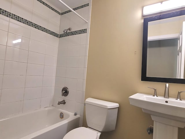 full bathroom featuring tiled shower / bath combo, toilet, and sink