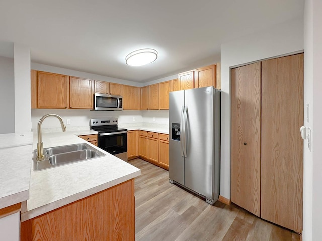 kitchen with light hardwood / wood-style floors, sink, and appliances with stainless steel finishes