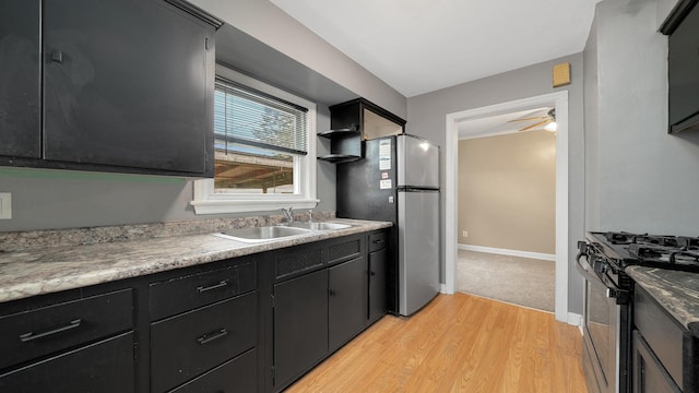 kitchen featuring ceiling fan, sink, light wood-type flooring, and stainless steel appliances