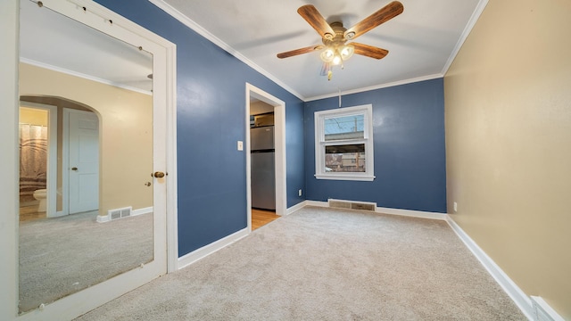 unfurnished bedroom with ensuite bath, light colored carpet, ceiling fan, crown molding, and stainless steel refrigerator