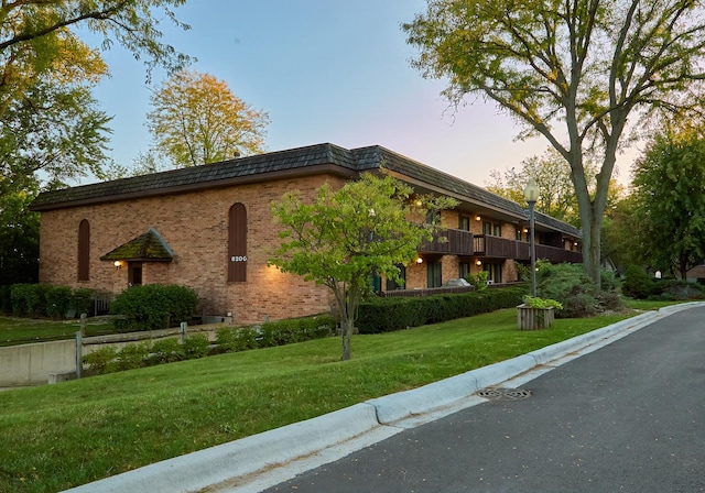 property exterior at dusk featuring a yard