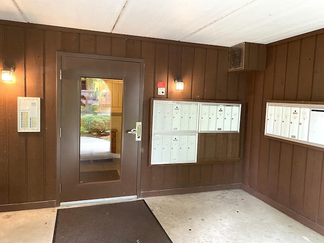 doorway to outside with a mail area and wooden walls