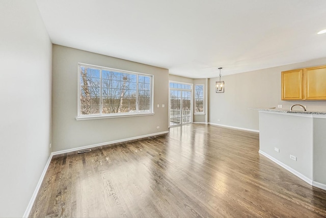 unfurnished room featuring hardwood / wood-style flooring, sink, and a chandelier