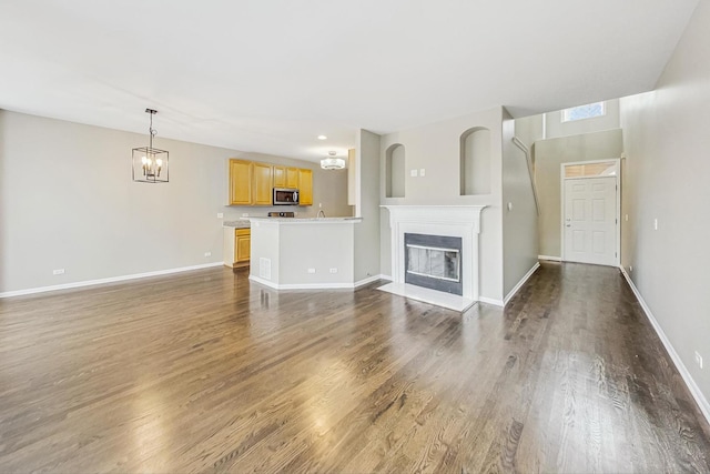 unfurnished living room featuring dark wood-type flooring and a notable chandelier