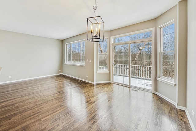 unfurnished dining area with dark wood-type flooring and a chandelier