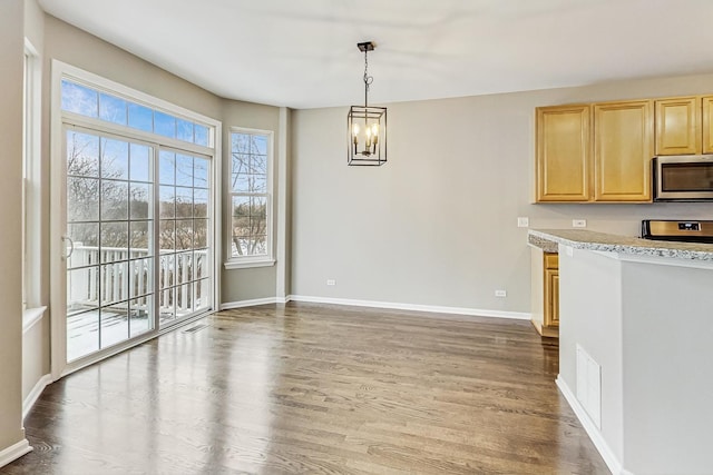 kitchen with hardwood / wood-style floors, light brown cabinets, decorative light fixtures, a notable chandelier, and range