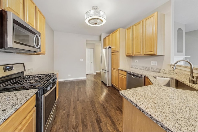 kitchen with light brown cabinets, light stone counters, sink, and appliances with stainless steel finishes