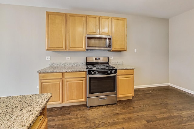 kitchen with light stone counters, stainless steel appliances, and dark hardwood / wood-style floors