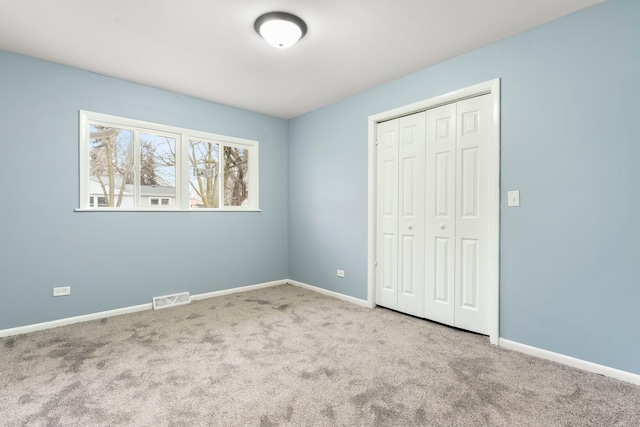 unfurnished bedroom featuring light carpet and a closet