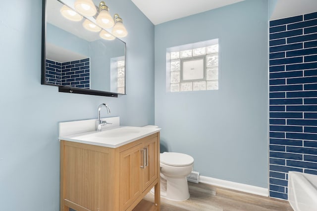 bathroom with a bath, wood-type flooring, vanity, and toilet