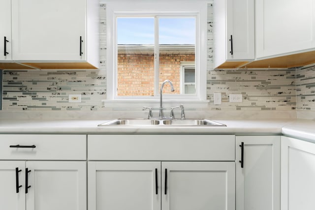 kitchen featuring white cabinets, sink, and tasteful backsplash