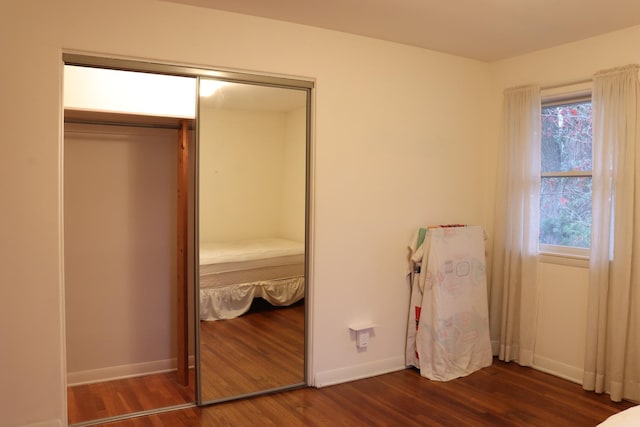 unfurnished bedroom with dark hardwood / wood-style floors and a closet