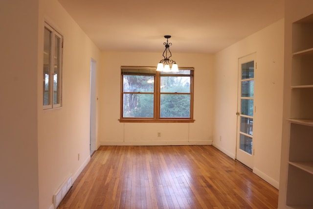 unfurnished dining area featuring hardwood / wood-style flooring and a notable chandelier