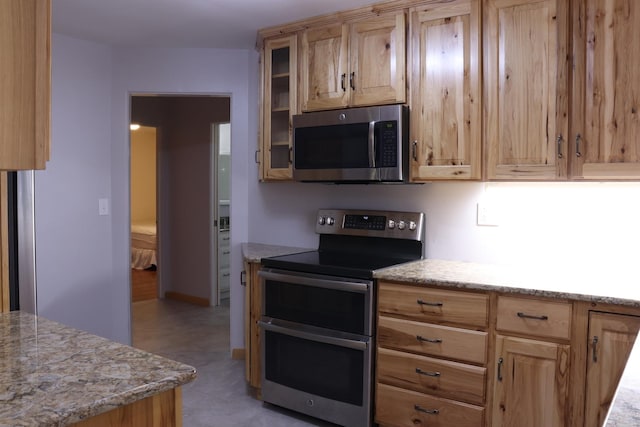 kitchen featuring light stone countertops, light brown cabinets, and stainless steel appliances