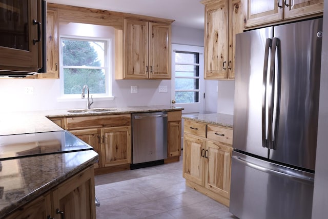 kitchen featuring stainless steel appliances, dark stone counters, and sink